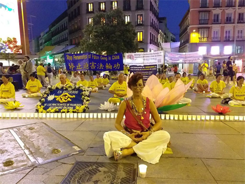 '圖3：2019年7月19日，在馬德裏Callao廣場，Vivian Acosta女士和法輪功學員一起，席地而坐，燭光守夜。'