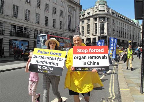 '圖6：英國法輪功學員澤克（Zek，右）走在倫敦「反迫害二十週年」遊行隊伍中，他從一九九八年開始修煉法輪功，二十年來一直在呼籲英國民眾和國際社會關注中共迫害法輪功反人類罪行。'