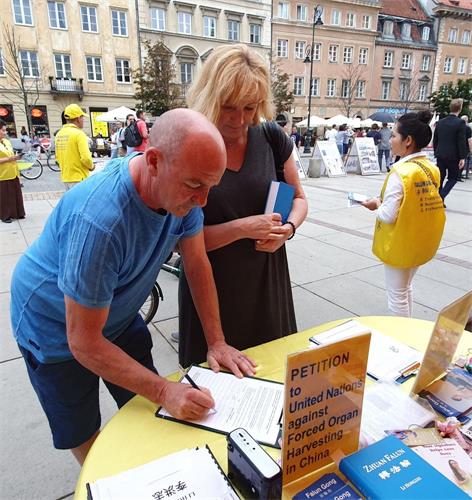 '圖16：購買《轉法輪》的波蘭夫婦在請願書上簽名，反對中共迫害法輪功'
