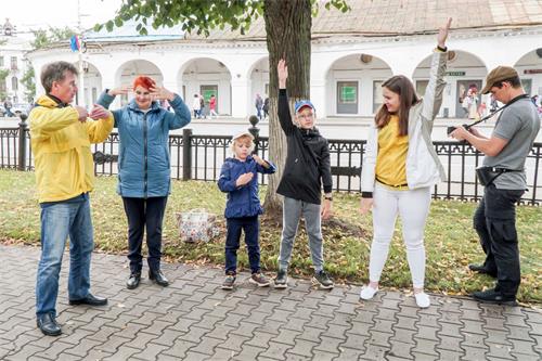 '圖10～11：法輪功學員在市政府對面的巴特尼科夫（Botnikovsky）中心花園展示功法，觀眾現場學煉法輪功。'