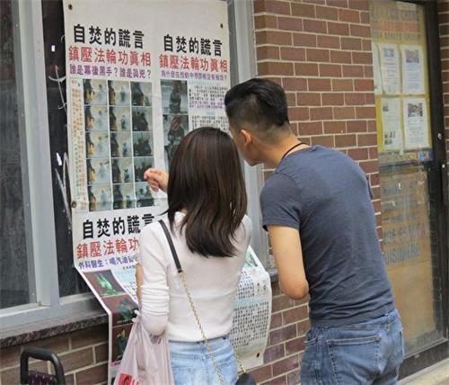 '圖2：一位年輕華人在與女友觀看海報時，認為中共對法輪功的迫害「沒有人性」。'