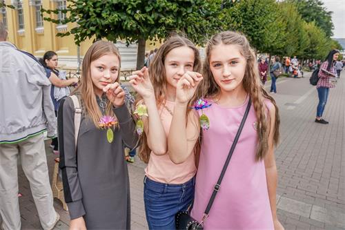 '圖8：從左至右：基斯洛沃茨克市年輕人柏麗娜（Polina）索菲亞（Sofia）和 維諾尼雅（ Veronika） 手舉和法輪功學員一起摺疊的紙蓮花'