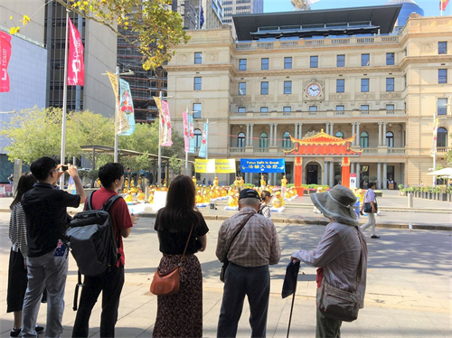 '圖1：在悉尼市中心海關大樓前行人或遊客駐足觀看法輪功學員展示法輪大五套功法'