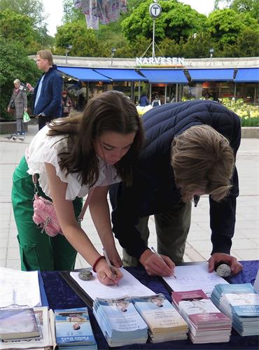 '圖6：五月九日，挪威民眾在在一份呼籲挪威國會和政府幫助制止中共活體摘取法輪功學員器官的呼籲書上簽名'