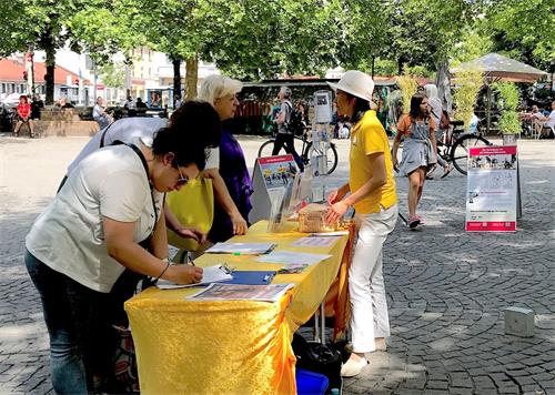 '圖4～5：法輪功學員在慕尼黑居民區紅十字廣場（Rotkreuzplatz）舉辦講真相活動'