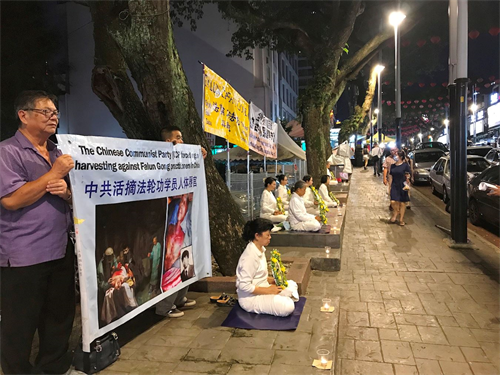 '圖5～6：七月十九日晚上，部份法輪功學員在吉隆坡亞羅街（Jalan Alor），悼念被中共迫害的法輪功學員。'