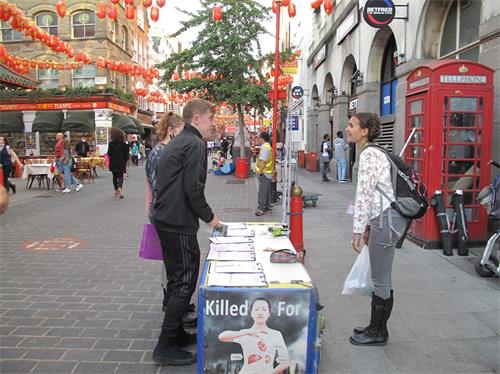 '圖9：二零二零年八月十六日，在倫敦唐人街，英國女演員愛琳（Eileen Von Skopnik）看到兩位青年走近法輪功信息台，她走上前去鼓勵他們簽名支持法輪功反迫害'