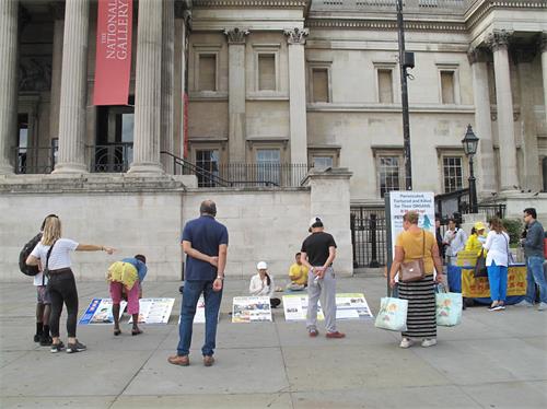'圖1～3：二零二零年八月二十二日，英國法輪功學員在倫敦特拉法加廣場（Trafalgar Square）北平台開展講真相反迫害活動，民眾駐足觀看、了解真相，簽名支持制止迫害。'