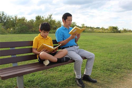 '圖2：楊國賢與小兒子一起讀《轉法輪》書'