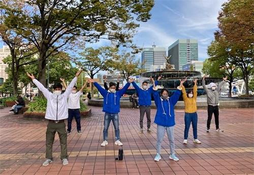 '圖1～2：二零二一年十月二十四日（星期日），日本中部地區法輪功學員在名古屋市（Nagoya-City）最繁華地段──榮（Sakae）的噴水附近集體煉功，向過往行人傳播法輪功的真相。'