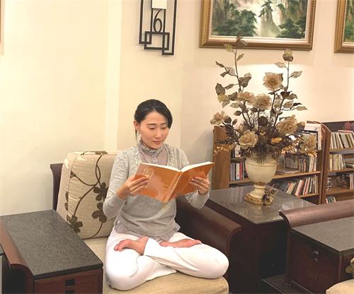 '圖1：王郁青老師從《轉法輪》一書中重新擁有煥然一新的人生。圖為她正在閱讀《轉法輪》。'