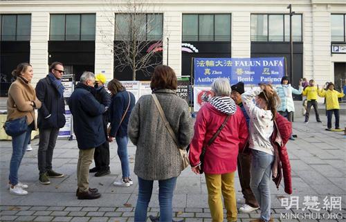 '圖3：二零二一年十一月十四日，在巴黎新橋地鐵站的信息日活動期間，人們駐足觀看，了解法輪功真相。'