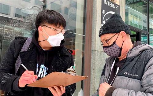 '圖9：韓國青年（左）非常贊同遊行傳遞的信息，在呼籲制裁中共的徵簽板上簽字。'