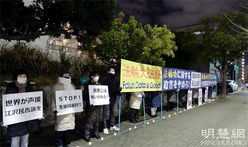 '圖1：二零二一年十二月三十一日，日本熊本地區法輪功學員在九州地區的中領館前展示真相橫幅，呼籲停止迫害。'