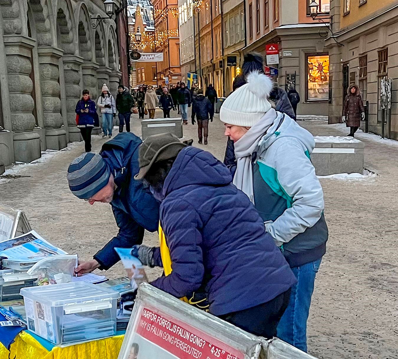 '圖5～6：二零二二年十二月十六日，法輪功學員在瑞典國會大廈旁舉辦講真相活動，明白了真相的人們主動簽名支持法輪功反迫害。'
