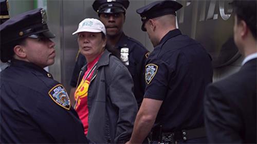 '圖3：二零一六年五月十三日，李華紅（左二，帶白帽者）因為干擾法輪功的活動被紐約警察當場拘捕。（大紀元）'