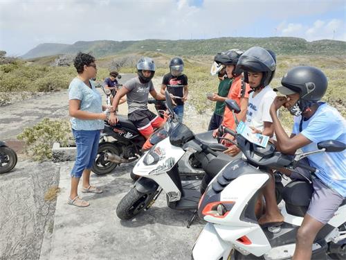 '圖：二零二一年三月二十八日，在瓜德羅普南部小島德斯拉德（la Désirade），法輪功學員（左一）向一群騎摩托車的人講法輪功真相。'