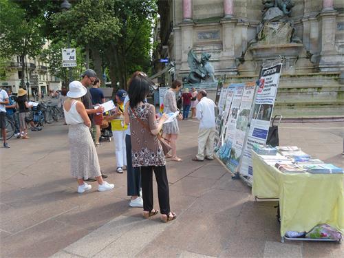 圖9：二零二二年六月十九日，在巴黎聖米歇爾廣場（Place Saint-Michel），人們觀看展板，了解法輪功真相，簽名支持制止迫害。