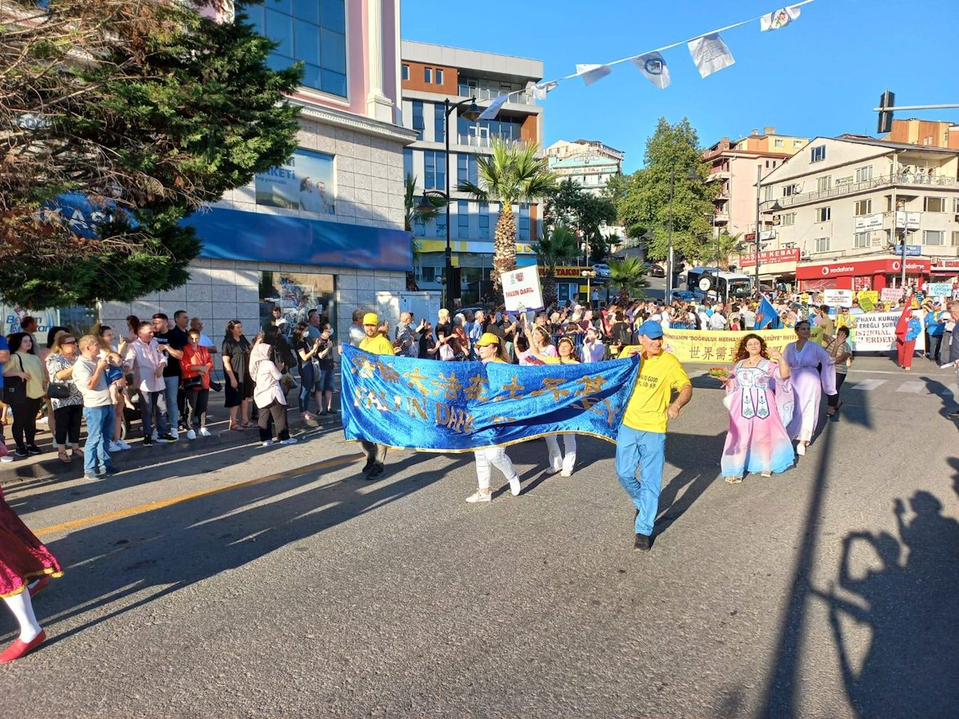 '圖2：七月二十一日，土耳其法輪功學員參加「愛、友誼與和平」國際文化藝術節的遊行，受到兩旁觀眾的歡迎，他們有的跟學員招手，有的鼓掌喝彩。'