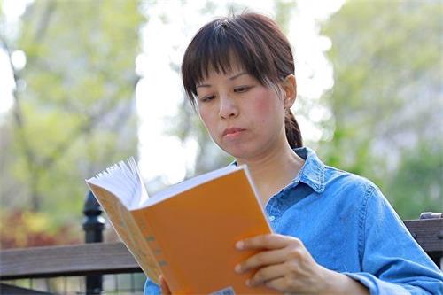 '圖5：法輪功學員劉慶在讀《轉法輪》。'