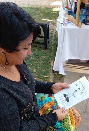 '圖3：用鉤針編織的手工藝人約翰娜﹒赫維亞（Johanna Hevia）在閱讀法輪大法傳單。'
